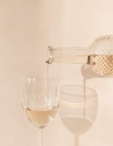 glass bottle pouring pale rose wine into wine glass