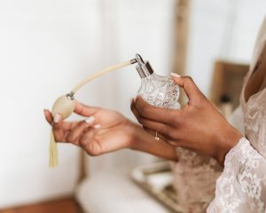 Woman with beautiful hands spraying perfume on chest