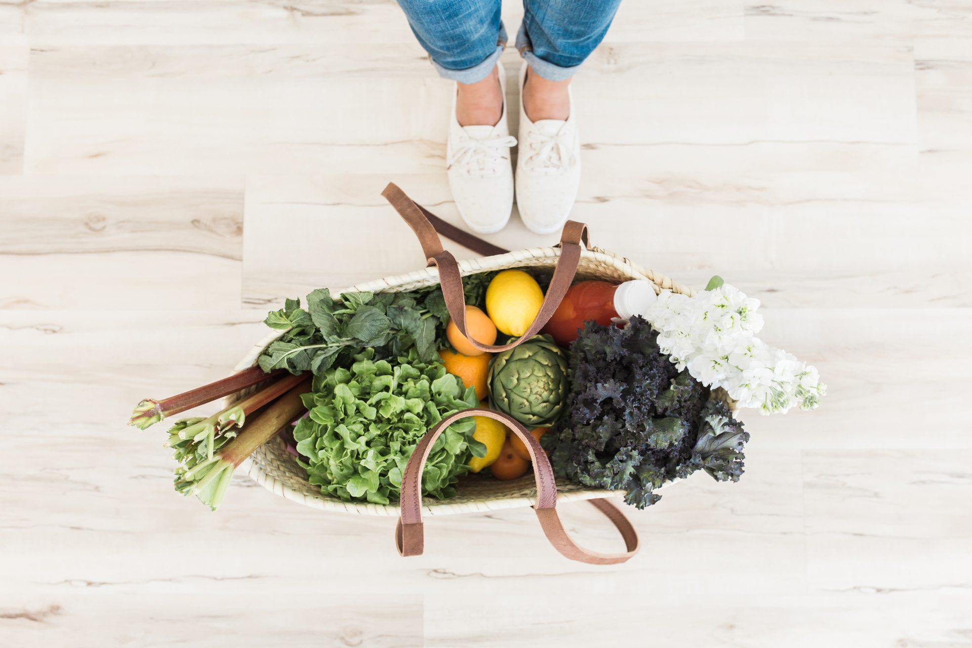 Woman in white shoes standing next to a bag of fruit and vegetables