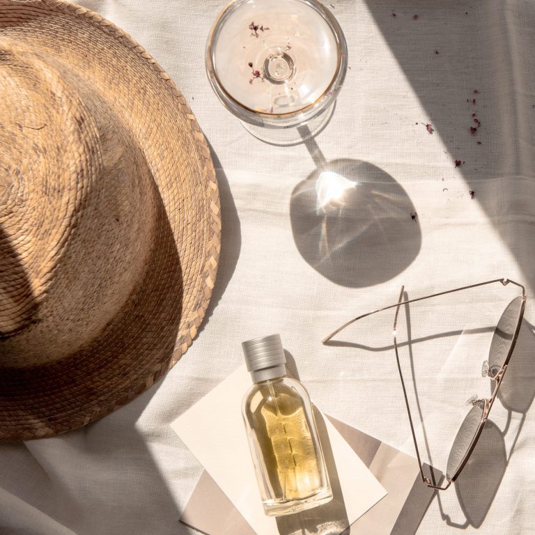 flat lay of summer essentials. hat, perfume, cocktail and sunglasses