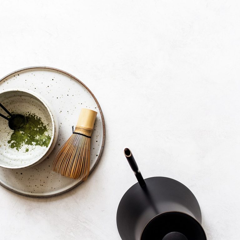 flatlay of ceremonial matcha powder in bowl with whisk brush