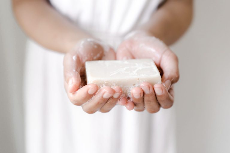 woman wearing white holding a white bar of soap in hands