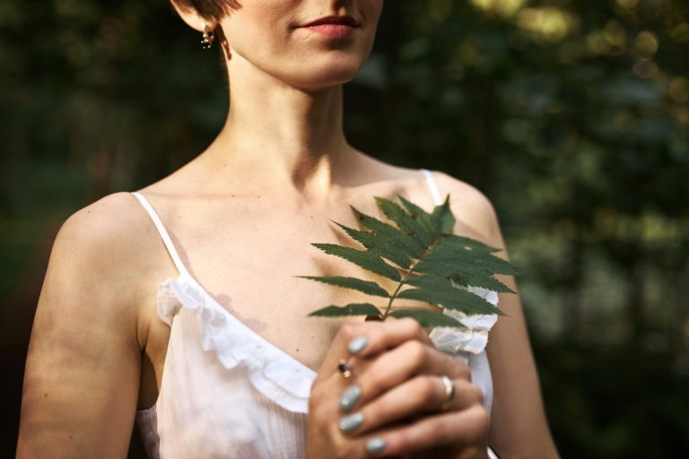 Beautiful young woman holding a green leaf