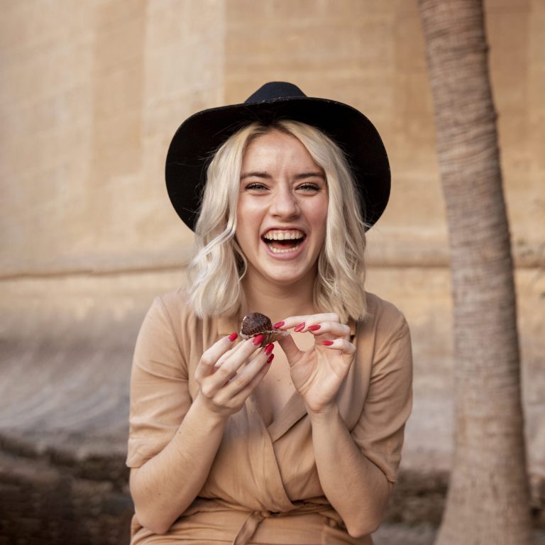 blonde woman wearing a hat and eating a cake