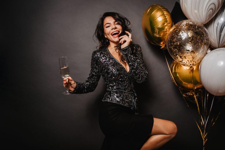 woman with dark hair at a party with glass of wine and balloons