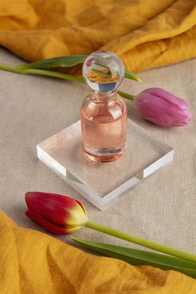 Flat lay of pink perfume bottle with pink tulips