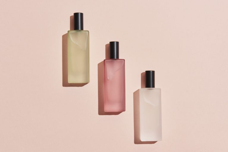 Flat lay of three perfume bottles on a pink background