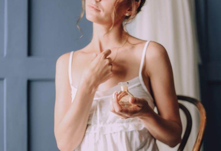 blonde woman applying perfume to chest