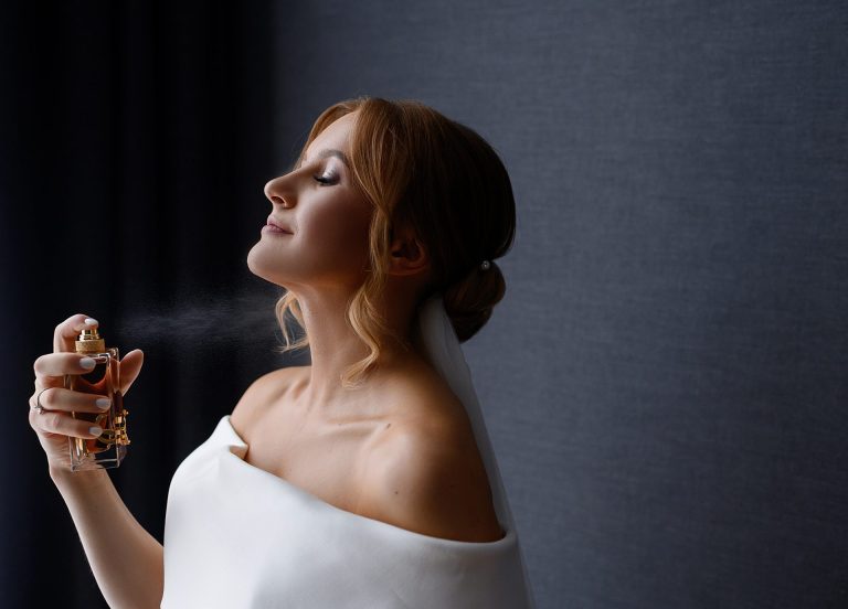 profile of bride spraying perfume onto neck