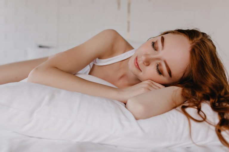 girl with red hair sleeping on a white pillow
