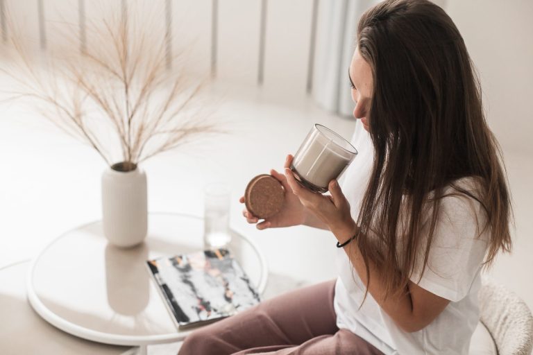 Young woman with dark hair smelling a candle
